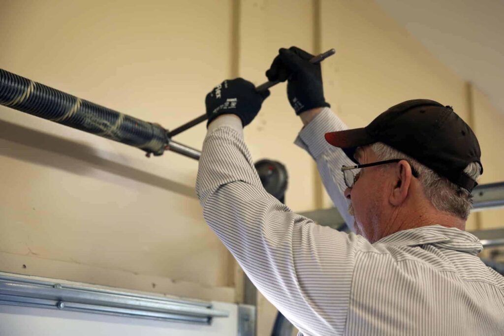 This Image depicts that a man is repairing an emergency garage door repair.