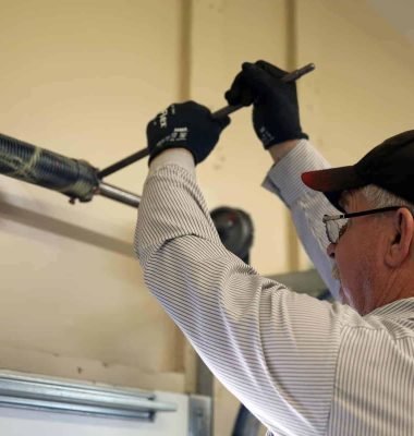 This Image depicts that a man is repairing an emergency garage door repair.